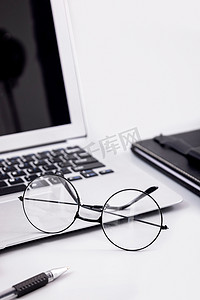 黑色海报背景素材摄影照片_现代时尚简洁办公眼镜笔记本素材摄影图配图
