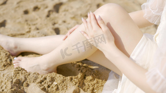 美女沙滩阳光涂抹防晒油腿部特写