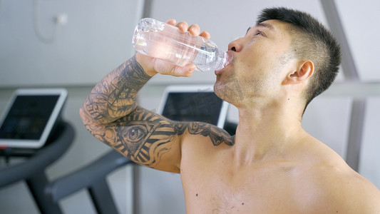 增肌摄影照片_健身教练健硕男运动员补充水分喝水营养