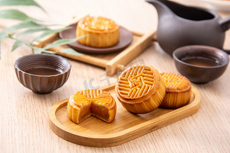 酥油蛋黄摄影照片_美食中秋月饼茶水室内木桌上摄影图配图