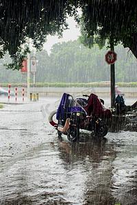 秋风秋雨摄影照片_白天户外电动车在暴雨下停驻摄影图配图
