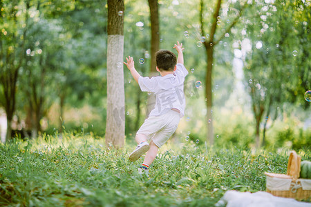 儿童玩耍白天小男孩户外草坪追泡泡摄影图配图