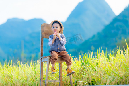 坐在椅子上开心的出西瓜的小男孩摄影图配图