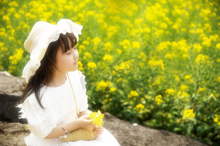 可爱治愈摄影照片_文艺唯美的小女孩坐在油菜花田里摄影图配图