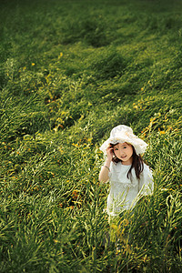 戴着帽子的小女孩愉快的在油菜花里玩耍摄影图配图