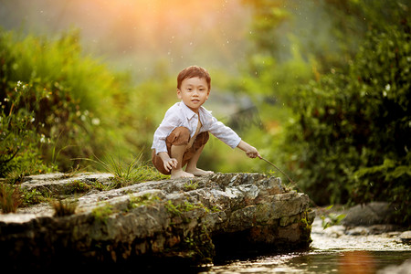 夏天小溪边开心玩耍的小男孩摄影图配图