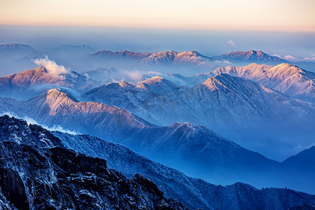 冬季新品火爆上市摄影照片_冬日旅行天亮雪山山区飘动摄影图配图