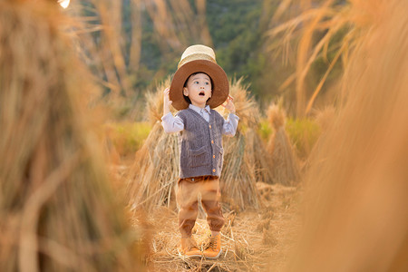 头顶背篼额男孩在稻田玩耍摄影图配图