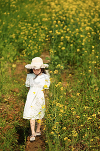 走在油菜花田的可爱的小女孩摄影图配图