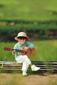认真弹吉他的小男孩白天摄影图配图