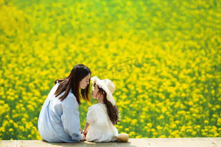 女神节快乐字体摄影照片_妈妈陪孩子在油菜花地开心的玩耍唯美摄影图配图