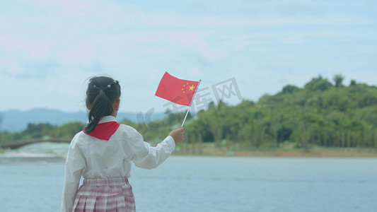 小学生手拿五星红旗站看向远方