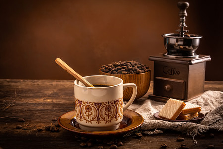 咖啡饮料摄影照片_美食饮品夜晚一杯咖啡甜点室内木桌上摄影图配图