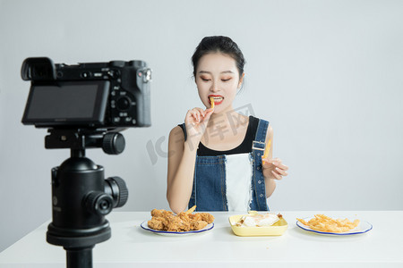 直播设备镜头前吃美食的主播平拍摄影图配图