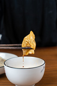 冬至水饺摄影照片_饺子白天蘸蒜泥的水饺室内吃水饺摄影图配图