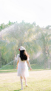阳光奔跑摄影照片_公园在草坪上奔跑的美女背影摄影图配图