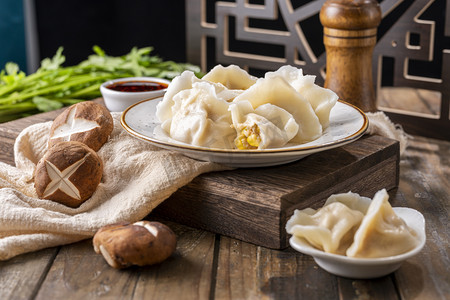 冬至水饺摄影照片_立冬冬至木桌上白色陶瓷碗里的玉米猪肉馅饺子摄影图配图