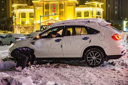 东北大雪摄影照片_东北大雪百年一遇两个人车车打滑铲雪摄影图配图