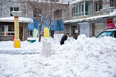 东北大雪摄影照片_辽宁冬天一个人铲雪街道铲雪摄影图配图