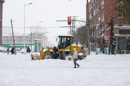 东北大雪摄影照片_东北上午铲雪车路口铲雪摄影图配图
