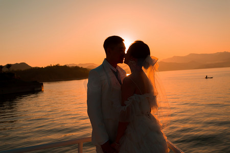 婚纱照剪影照片夕阳两个人户外亲吻摄影图配图