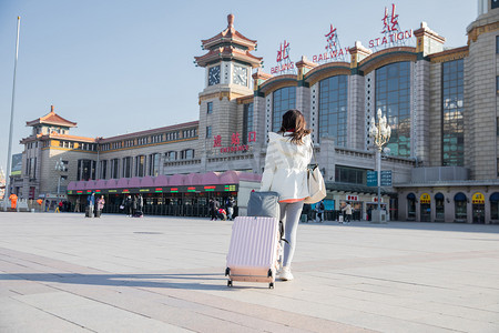 春运白天拖着行李箱的年轻女孩背影火车站进站摄影图配图