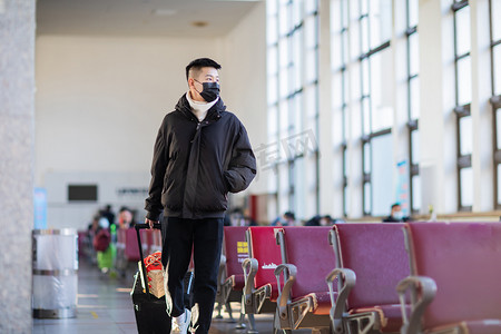 买票次图摄影照片_回家春运白天拉着行李箱的男青年候车室拉着行李箱摄影图配图