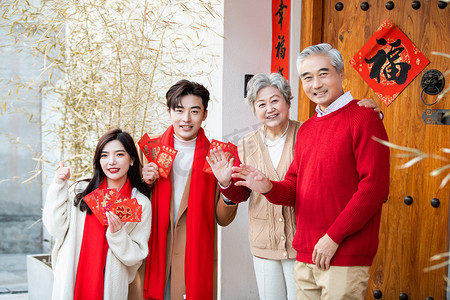 春节站在门口手拿红包的一家人摄影图配图