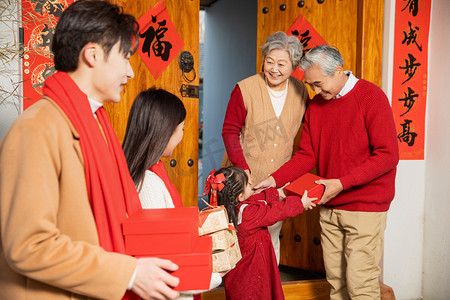 阖家团圆元素摄影照片_春节回家孙女给爷爷奶奶送礼物一家人开心摄影图配图