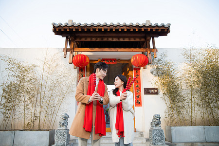 春节站在门口拜年的年轻情侣摄影图配图