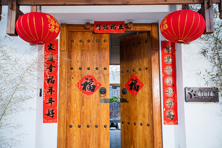 开门红贴图摄影照片_春节大红灯笼高高挂贴上对联的中式木门摄影图配图