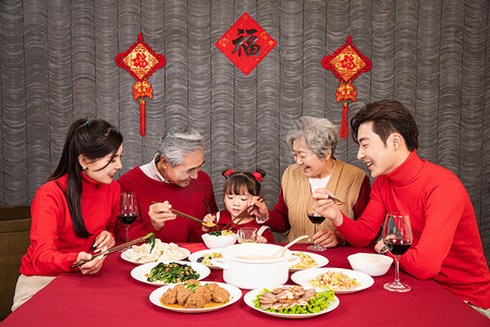 春节团圆摄影照片_幸福的一家五口吃年夜饭给孩子夹菜摄影图配图