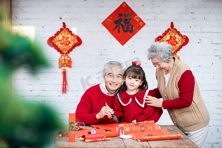 除夕奶奶陪着爷爷教小女孩写对联摄影图配图