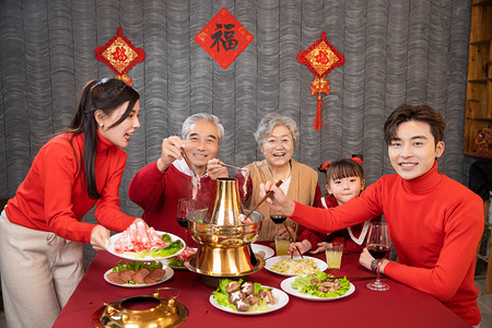 除夕龙年摄影照片_年夜饭一家人开心的吃火锅摄影图配图