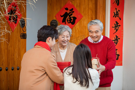 人物全家福摄影照片_春节带礼物回家看望爸妈的年轻夫妻摄影图配图