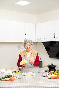 居家的老人在厨房里摘菜做饭摄影图配图
