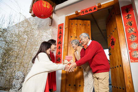 新年全家福摄影照片_年轻男女回家探亲给父母送礼物摄影图配图