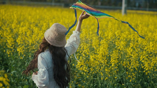 春天踏青春游摄影照片_唯美实拍少女在花海中奔跑放风筝背影实拍