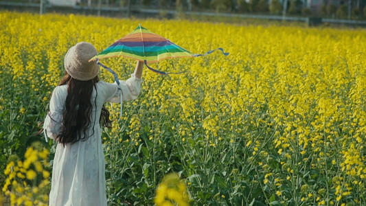 奔跑女孩摄影照片_实拍少女在花海中奔跑放风筝背影