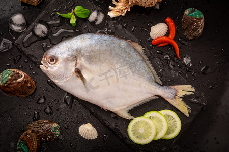 美食白天金鲳鱼黑色石板上摆放摄影图配图