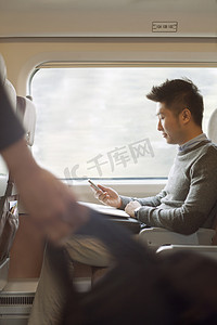坐火车摄影照片_男子坐在一列火车使用他的电话