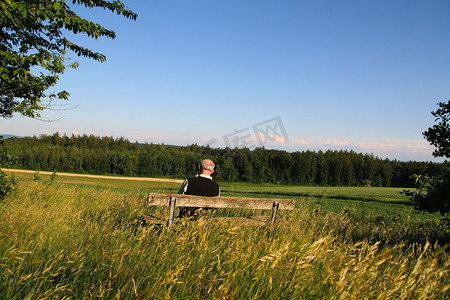 一个退休的老人坐在长椅读