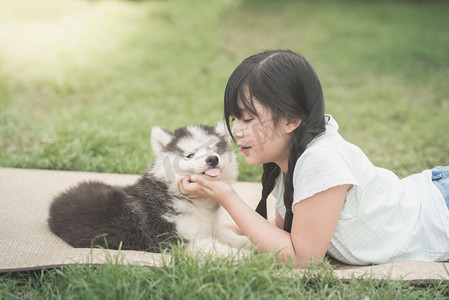 哈士奇摄影照片_美丽的亚洲女孩和西伯利亚哈士奇犬小狗一起玩 