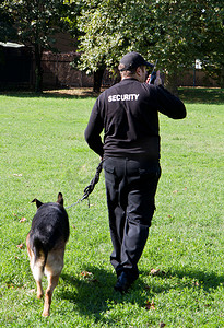 警察牵着警犬走在草坪上
