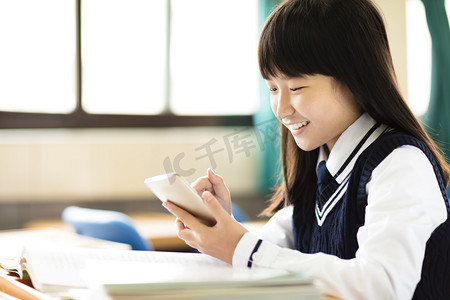 在教室里用智能手机快乐的女学生