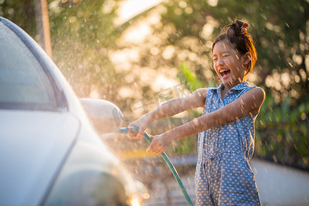快乐的亚洲女孩洗车水溅和阳光在家里