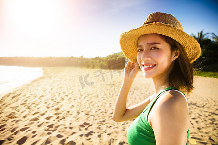 夏天日落时在海滩上散步的美丽的年轻女子