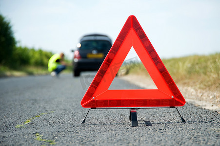汽车安全驾驶摄影照片_红色警告三角形，装有一辆抛锚的汽车