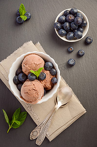 白色冰淇淋球摄影照片_黑色的石板背景上的白色碗巧克力冰激淋