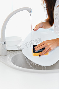 洗脸服务摄影照片_关闭了手洗碗在厨房里的女人